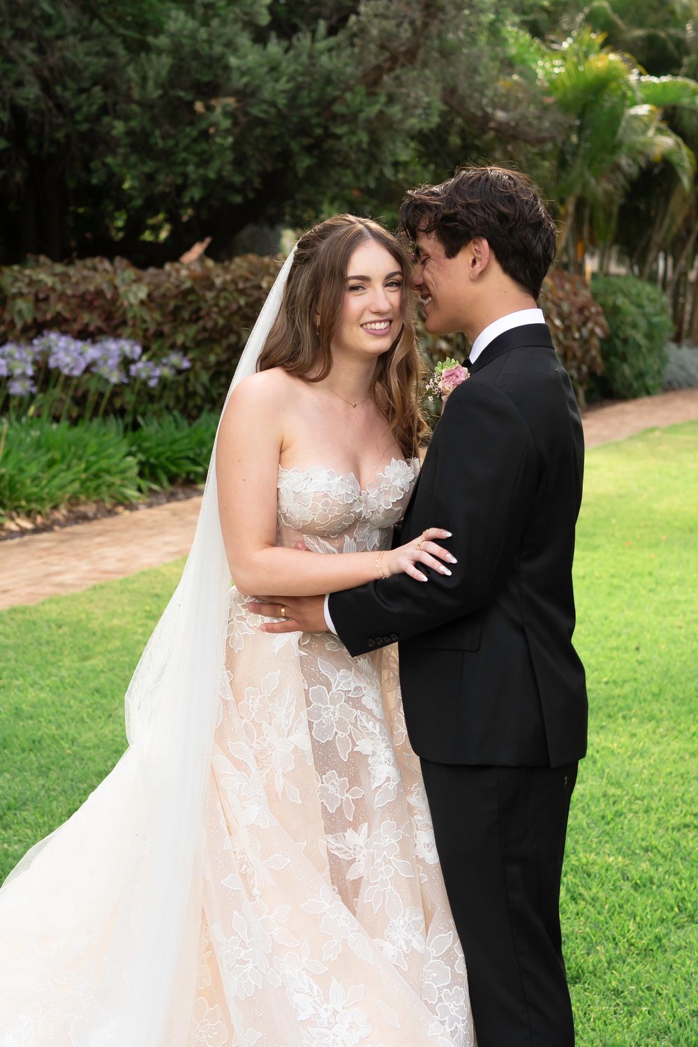 A couple shares intimate moments in a garden setting during their wedding photoshoot.