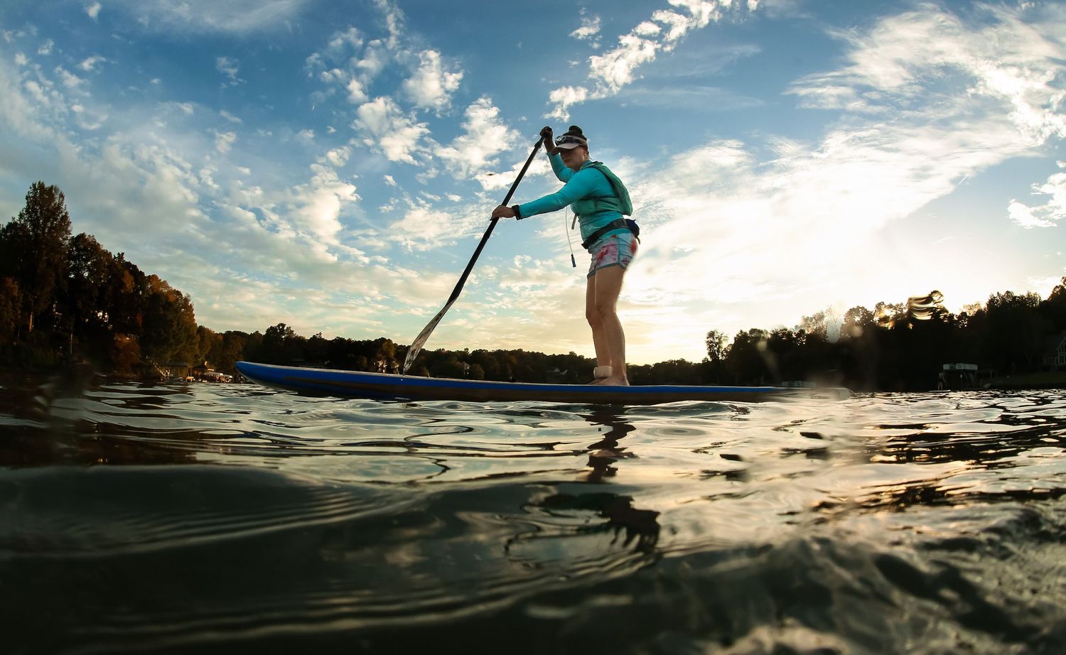 Paddleboarding on Lake Wylie during Goat Boaters practice, athlete balancing on board at sunset with calm water and scenic background.