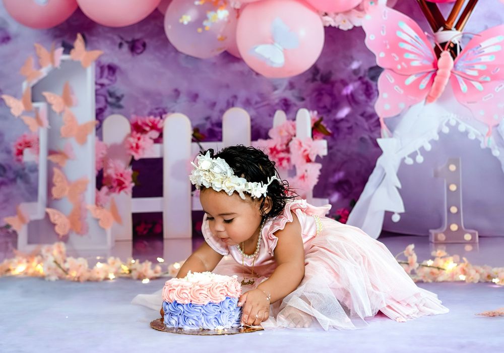 Pink and purple balloon decorations create a whimsical backdrop for a festive celebration with floral accents.