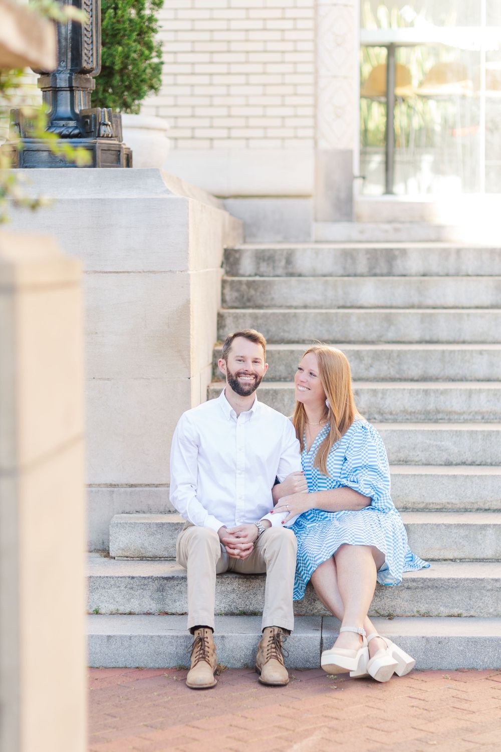 A couple shares a tender moment while sitting on concrete steps during a photo session.