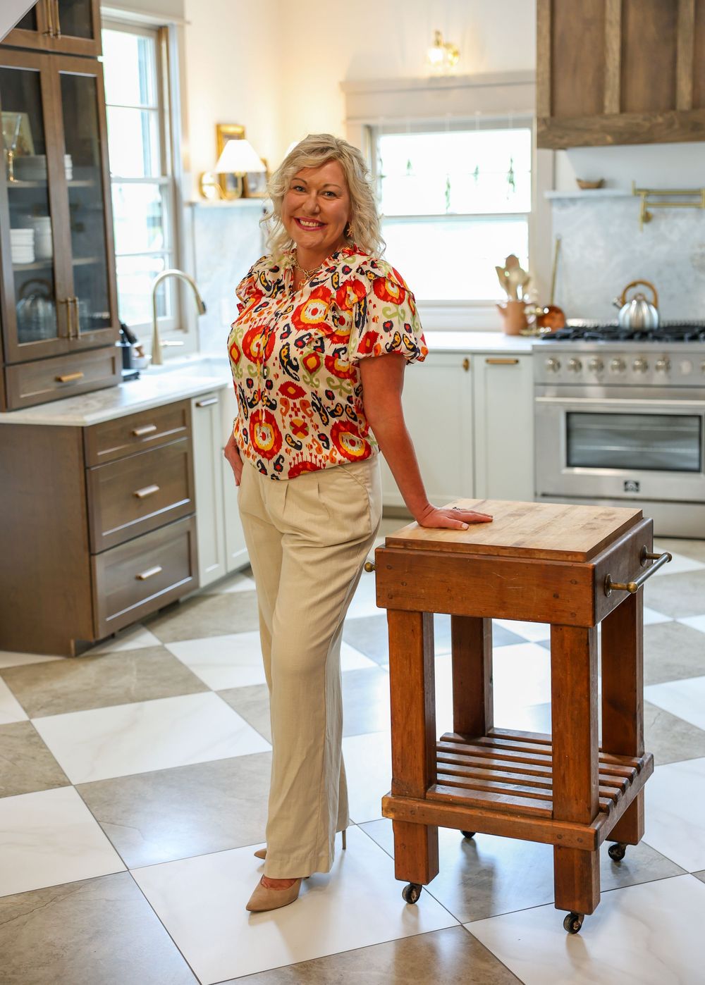 Kitchen scene with rolling wooden island and floral top against white cabinetry.