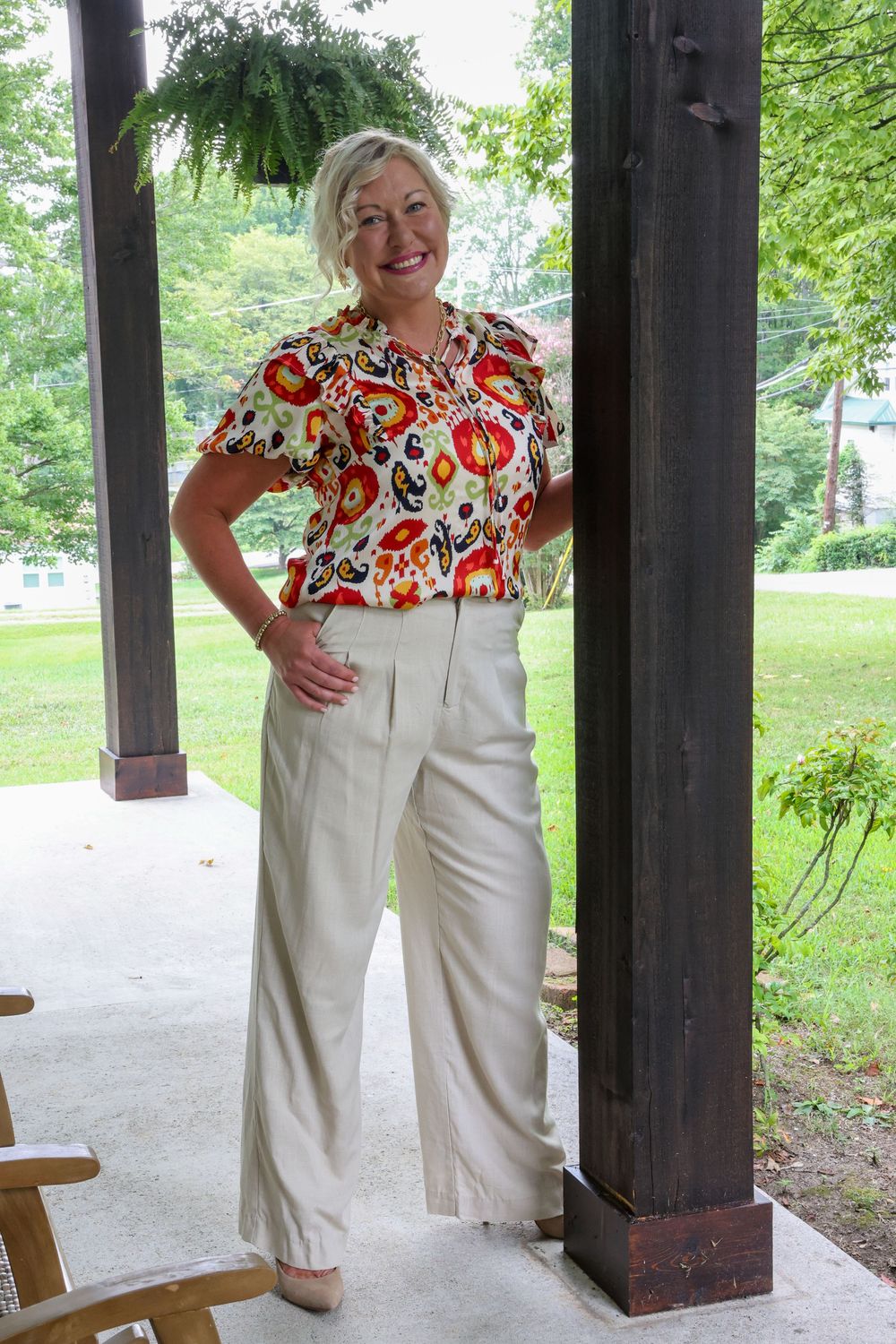 Outdoor porch photoshoot featuring floral ruffled top and white pants ensemble.