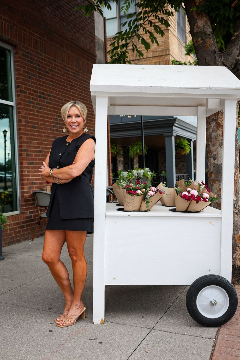 White outdoor cart display with decorative flowers and large wheels.