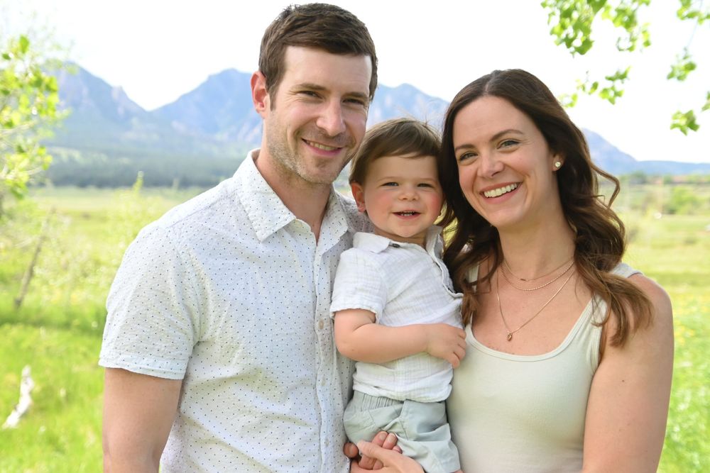 Family enjoys a sunny summer day together outdoors with mountains and lush greenery in the background.