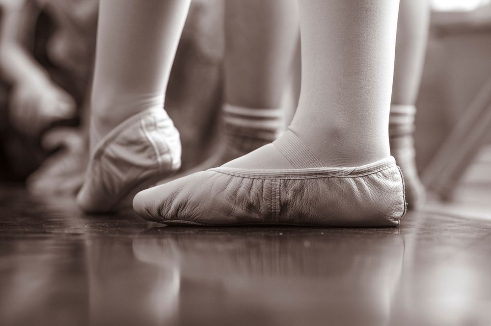 Close-up of ballet shoes on wooden floor in black and white.