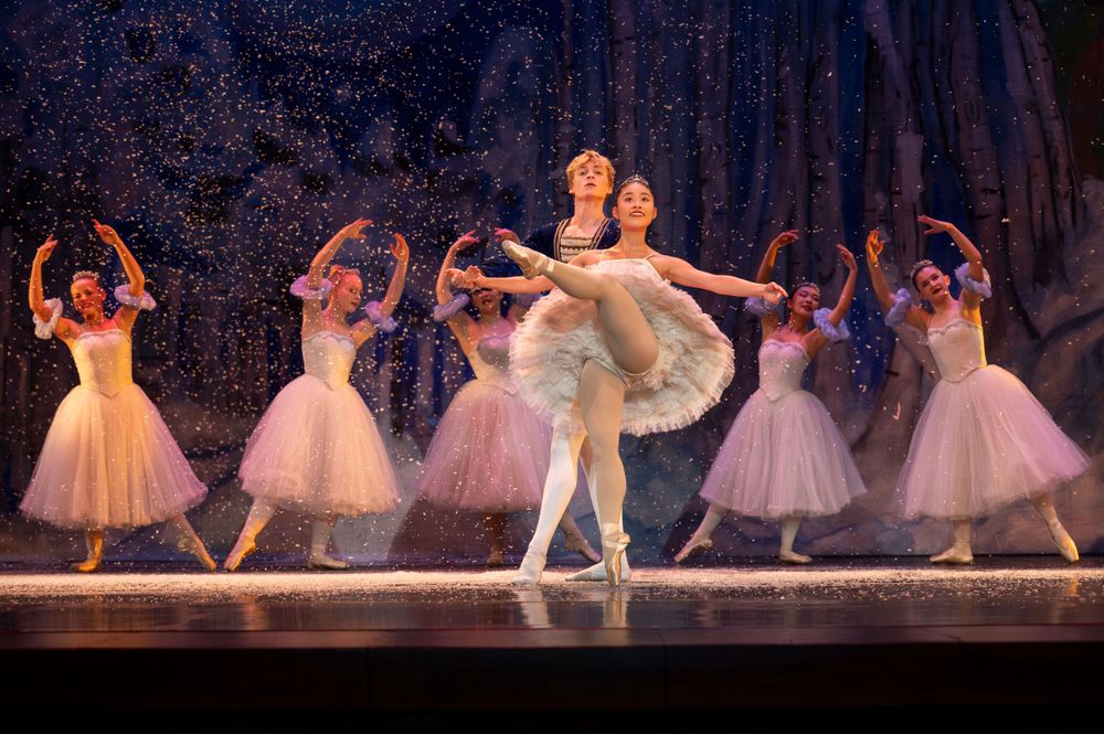 Ballet performance featuring dancers in white tutus during a romantic scene on stage.