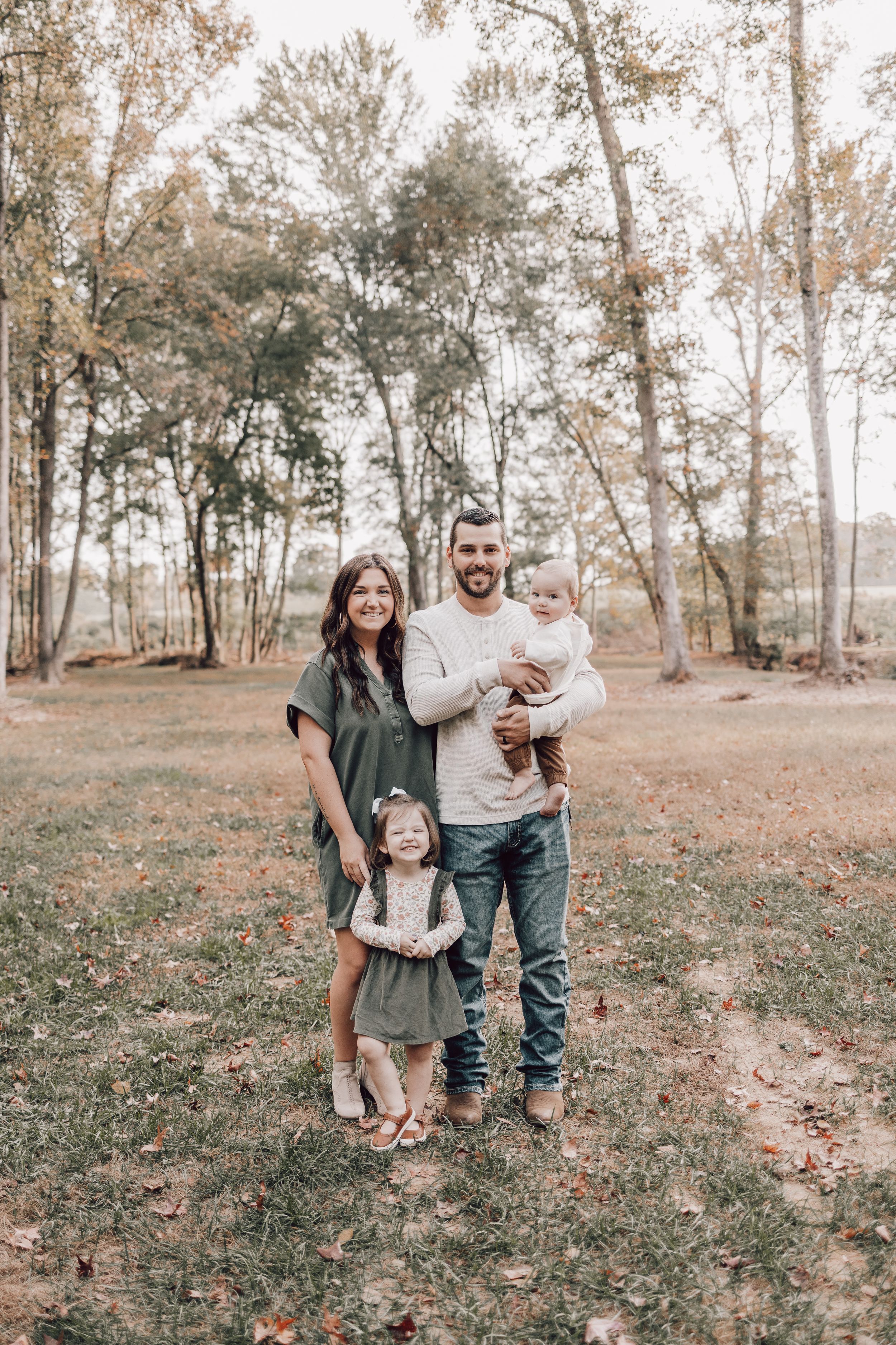 Family enjoying a casual autumn photoshoot outdoors among fall trees and foliage.