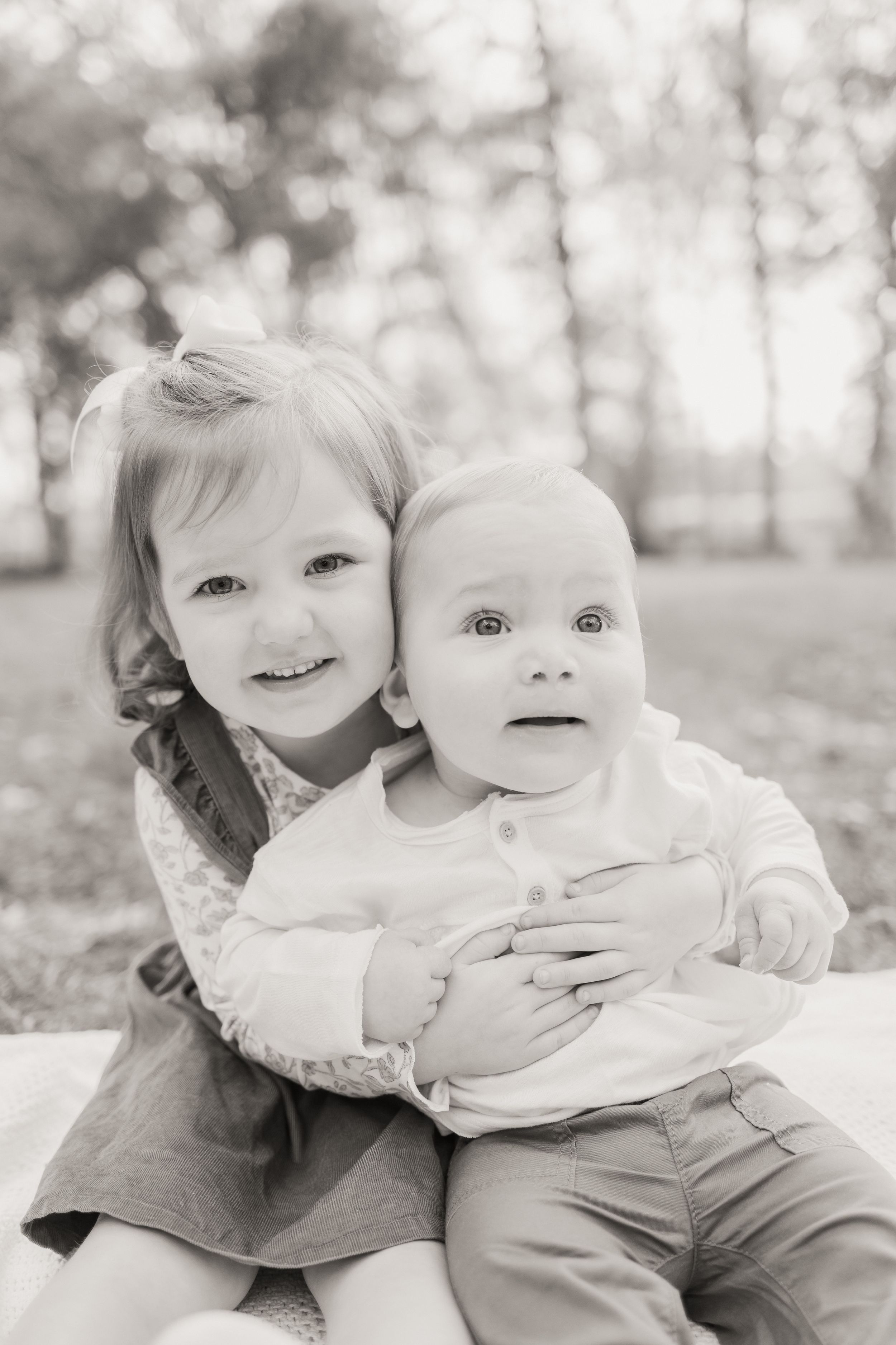 Sweet black and white photo series of siblings embracing and playing together outdoors in natural light.