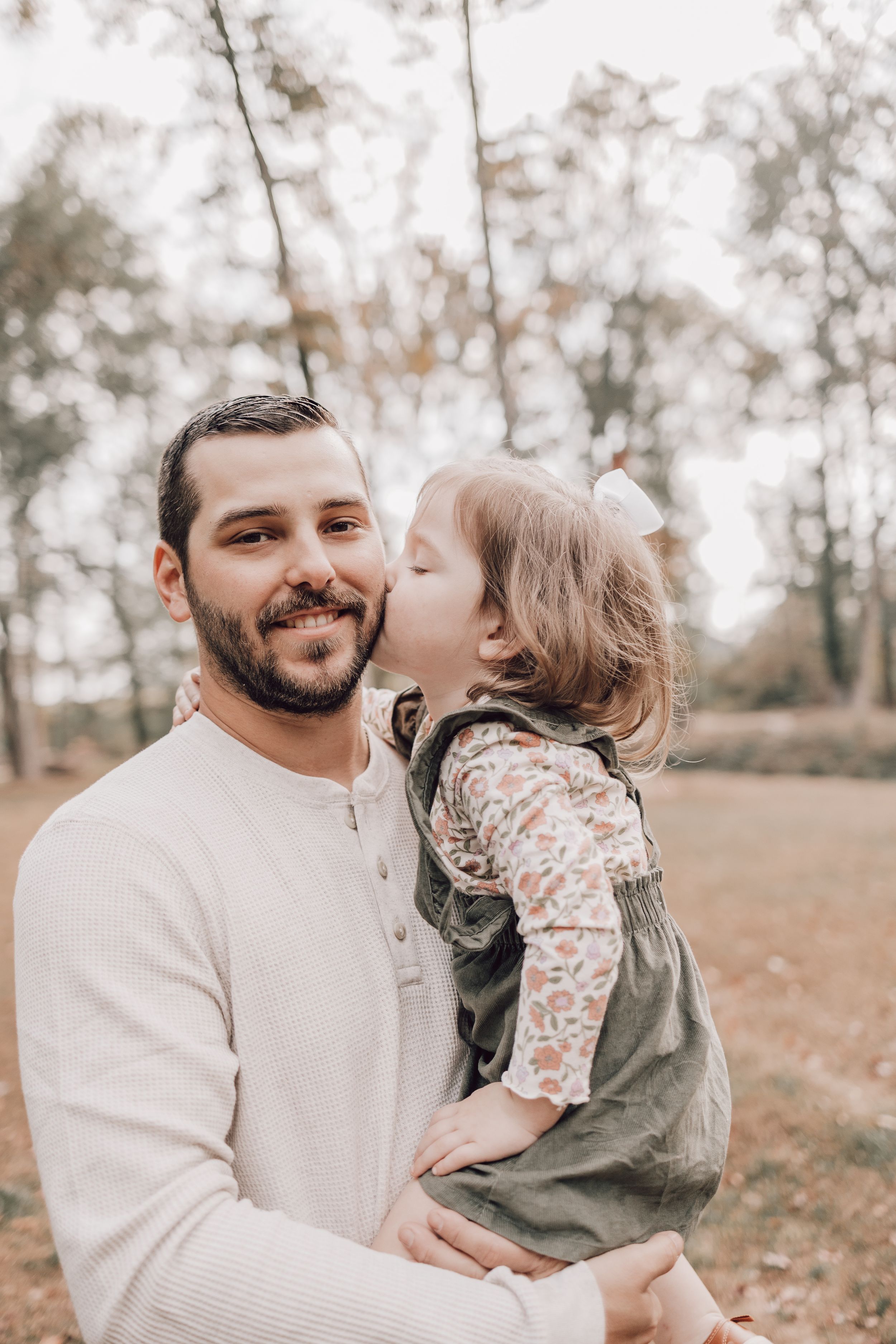 A heartwarming autumn photoshoot showing tender family moments between parent and child in a park with fallen leaves.