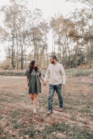 A family walking together and sharing sweet moments on an autumn day surrounded by bare trees and fallen leaves.