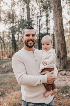 A tender moment captured in autumn woods with a cream sweater and warm smiles.
