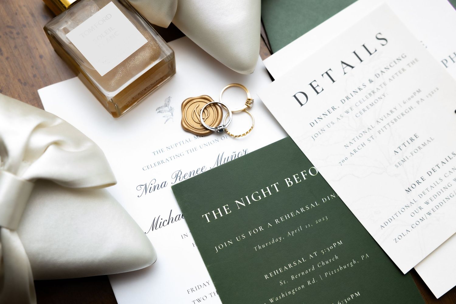 Wedding stationery flat lay with rings and green details card.