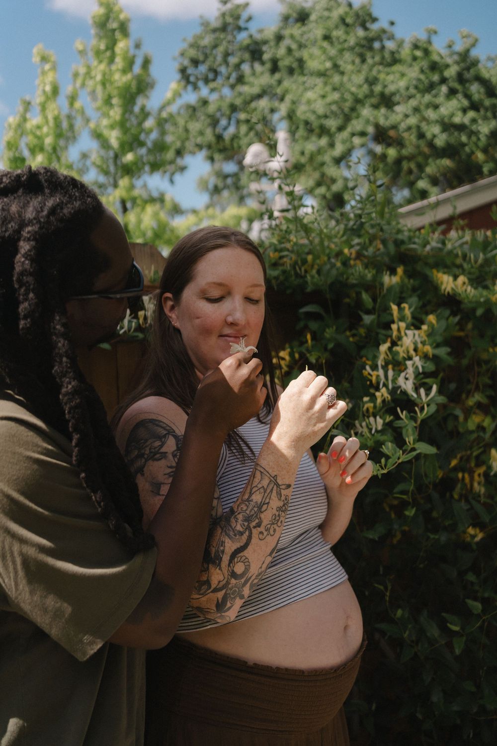 Man and woman smelling flowers in the yard
