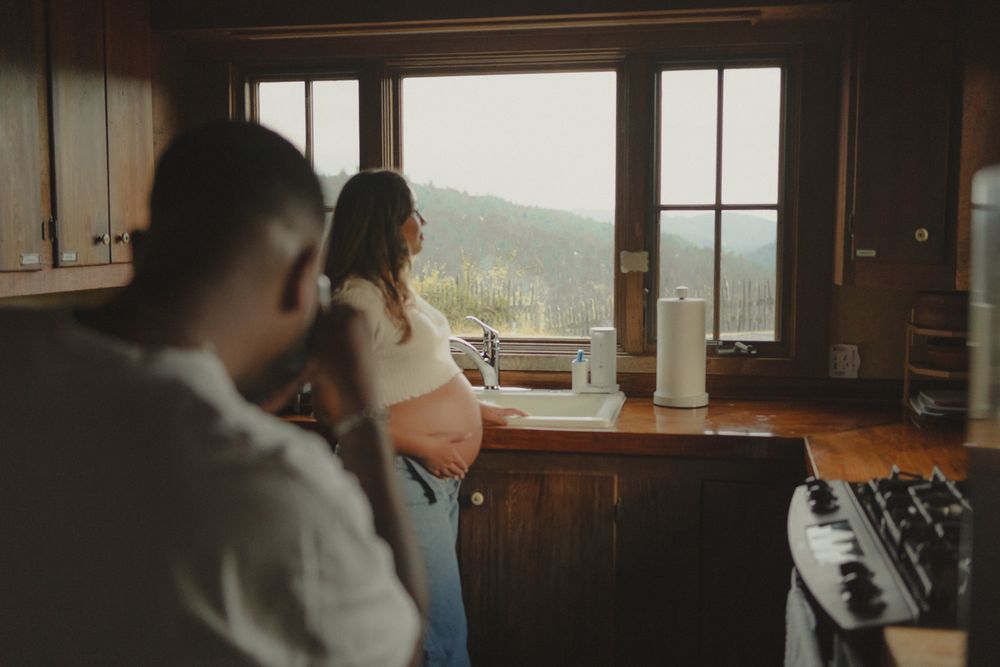 man taking a picture of a pregnant woman in the kitchen