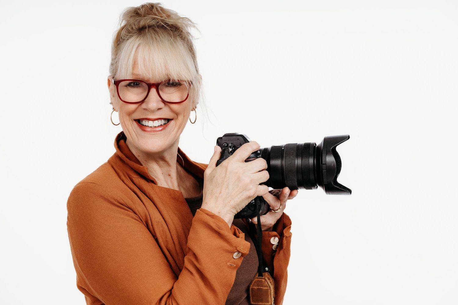 Photographer in red off-shoulder top and headband using professional camera.