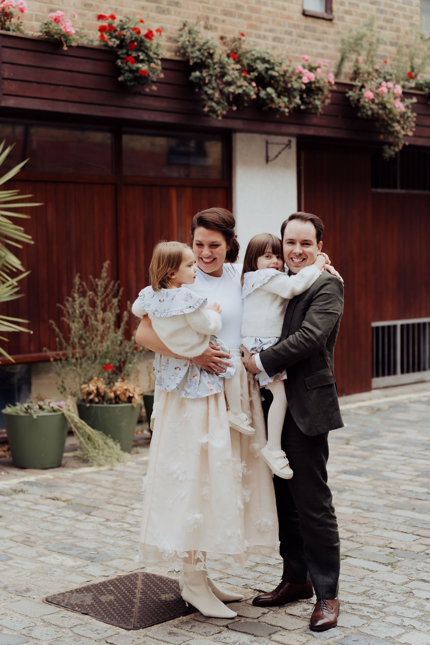 A couple shares a joyful first look moment in their wedding attire on a stone patio with floral decorations.