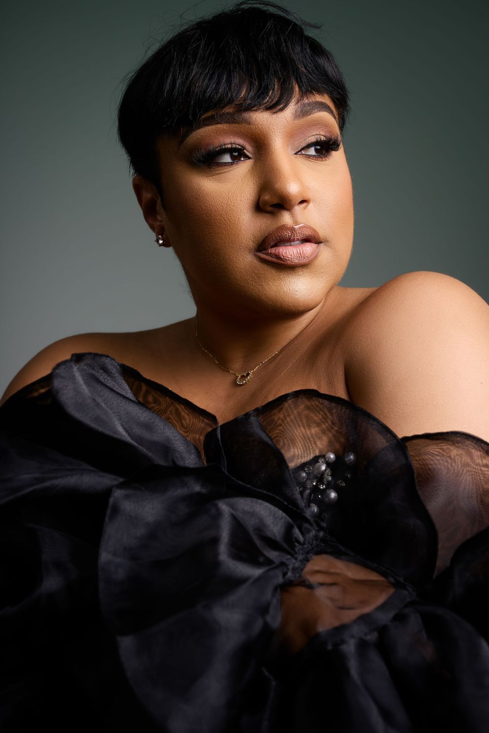 Glamorous portrait in black evening wear against moody studio lighting.