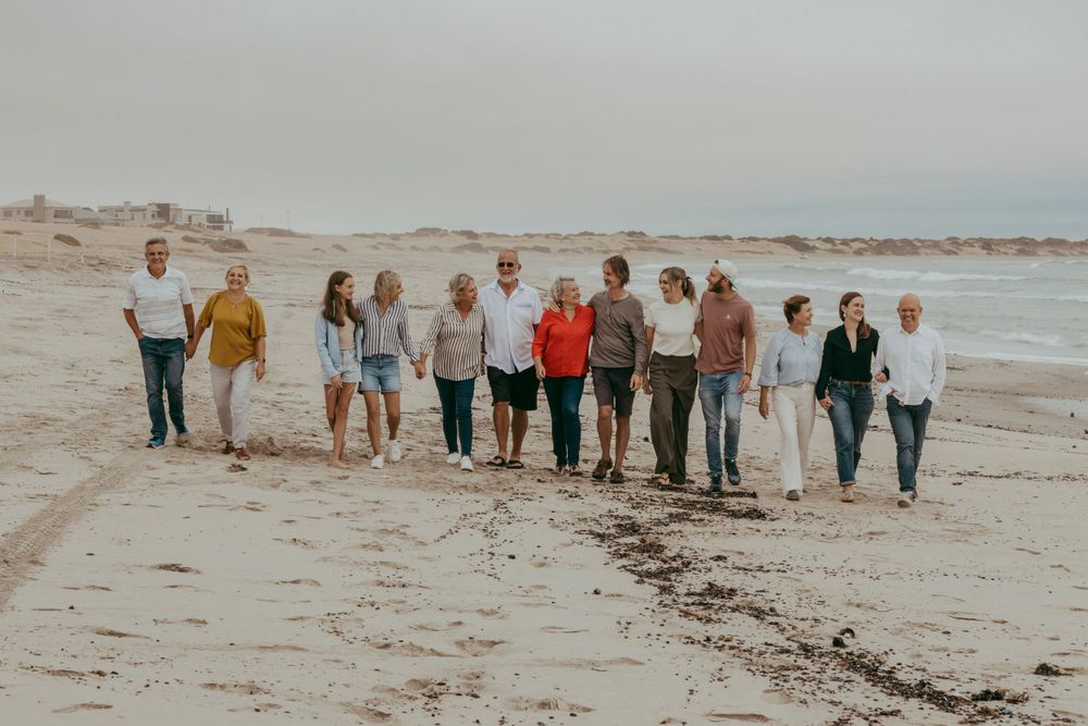 A family enjoying a photoshoot on Henties Bay beach, with the ocean waves and sandy shoreline creating a beautiful coastal backdrop