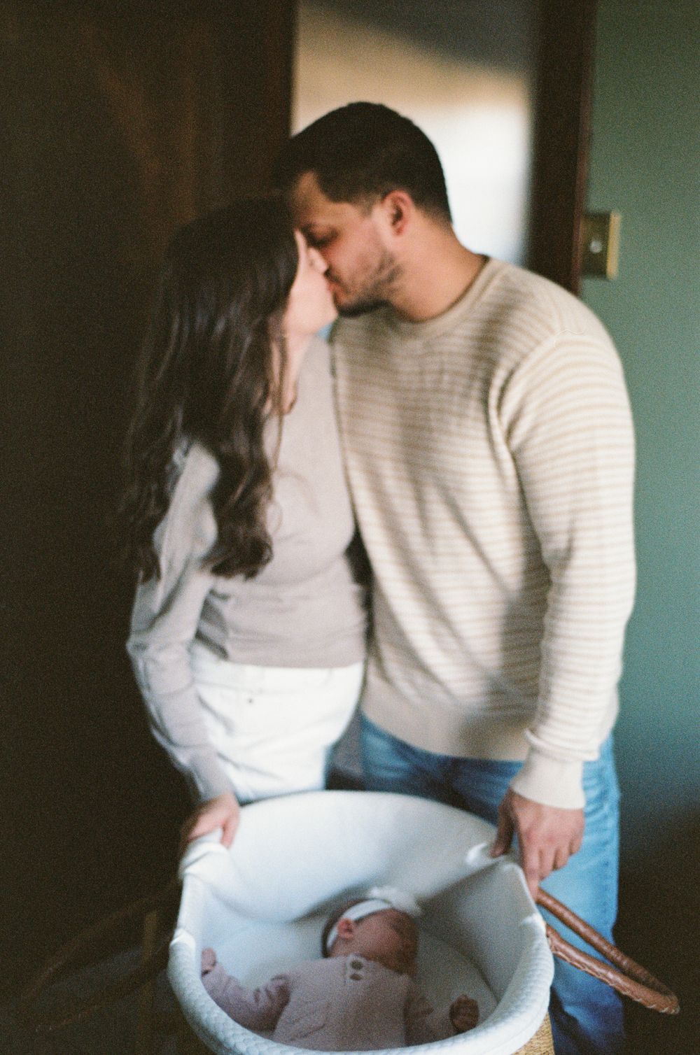 An intimate moment shared between a couple as they stand near a baby bath tub during bath time.