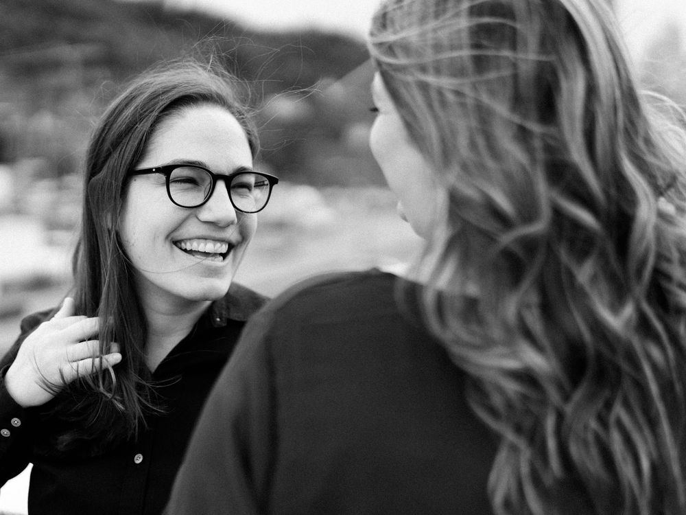 A candid black and white photo shows two people sharing a joyful moment together outdoors.