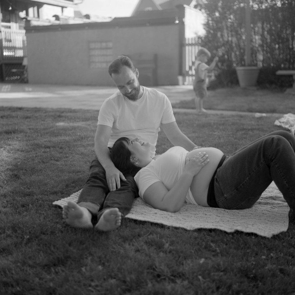 Two people relaxing on a blanket outdoors in a black and white vintage photograph.