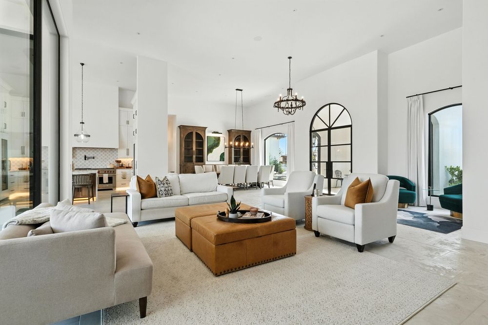 Modern white living room with coastal views features plush seating, wood coffee table and arched doorway in luxury home.