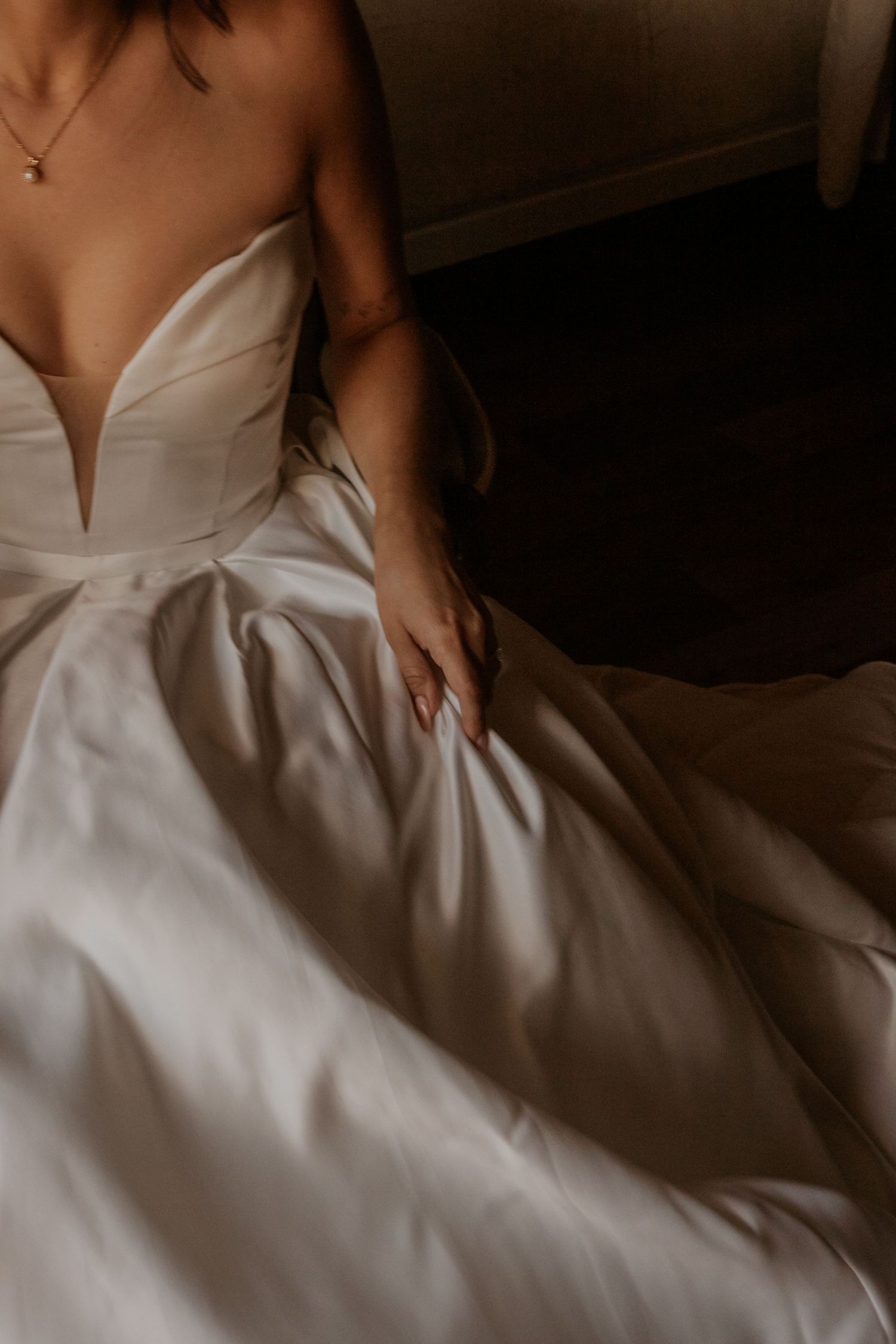 Close-up detail of a white wedding dress bodice and flowing skirt.