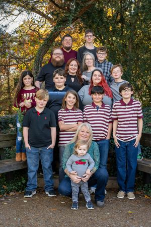 Family group photo session outdoors during autumn with coordinating red and white striped outfits in a park setting.