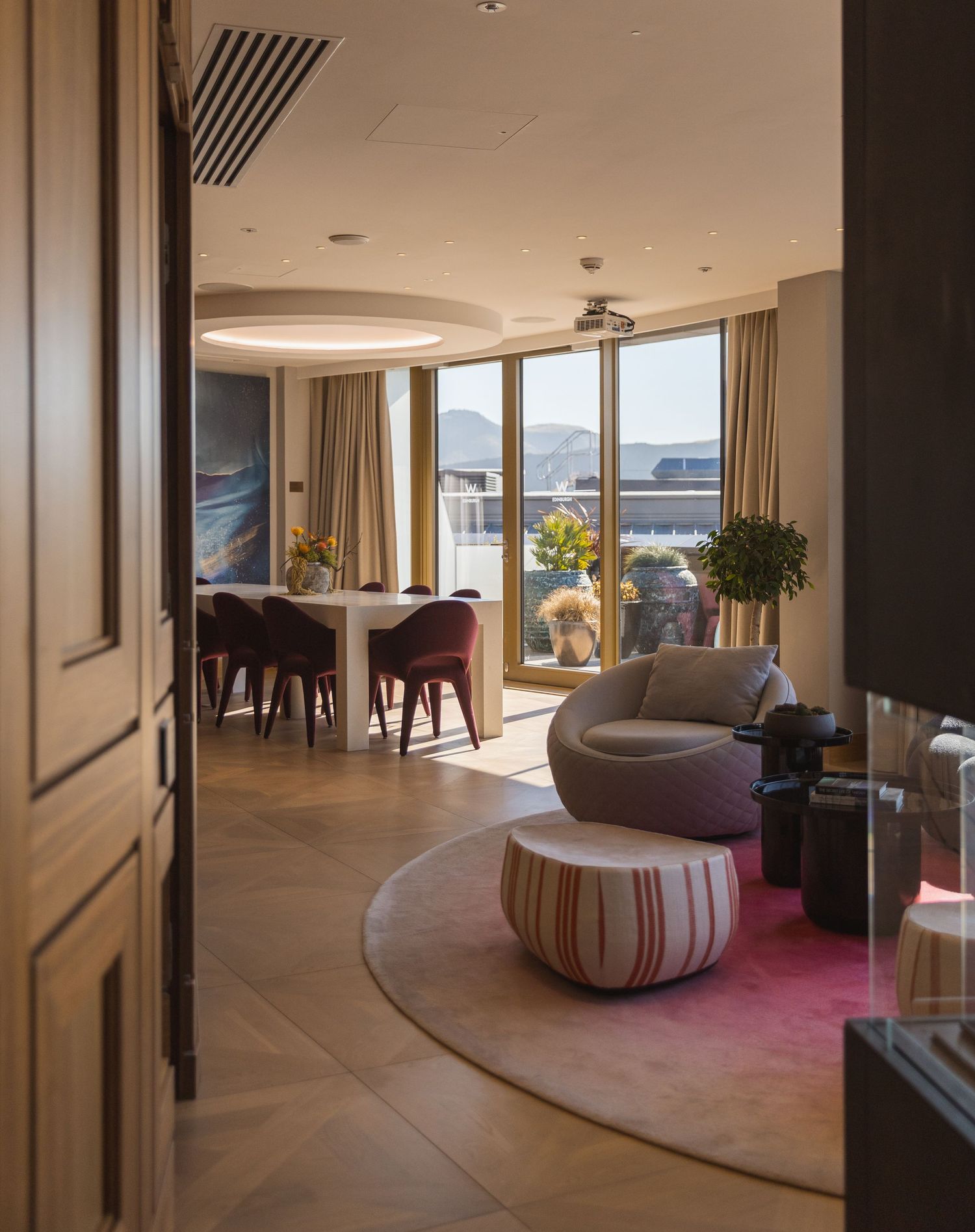 Modern luxury hotel suite interior with panoramic windows and contemporary furnishings.