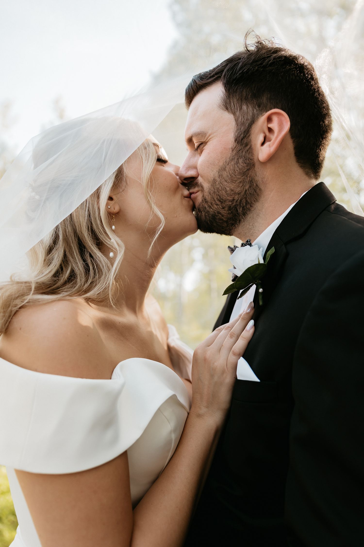 Intimate wedding moment captured with soft lighting and white floral backdrop.