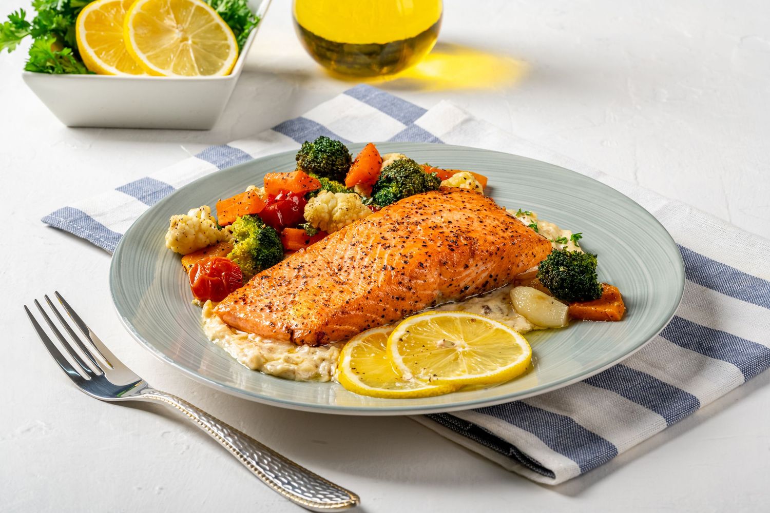 Pan-seared salmon fillet served with lemon and vegetables on white plates.