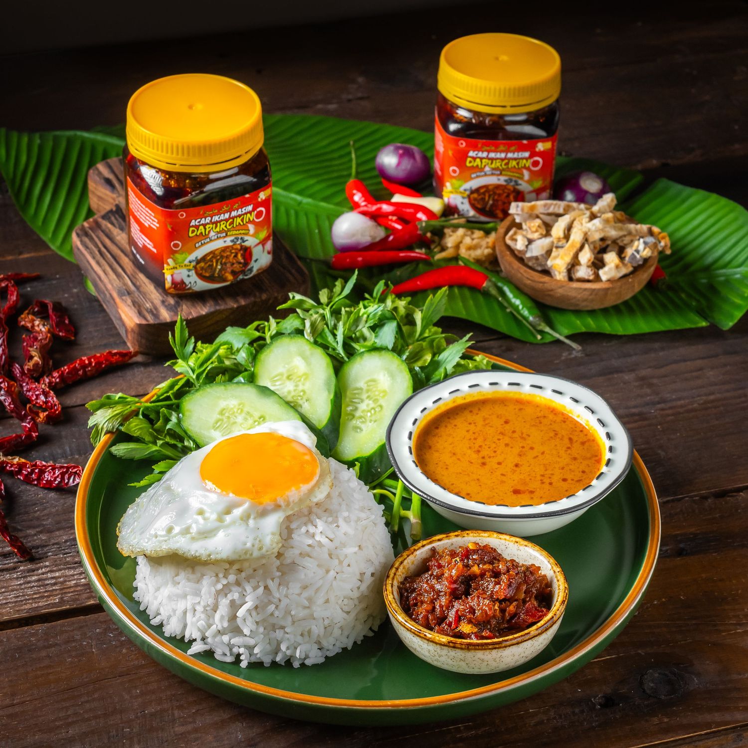 Traditional Asian rice plate with sambal, fried egg, cucumber and spicy condiments on banana leaf.