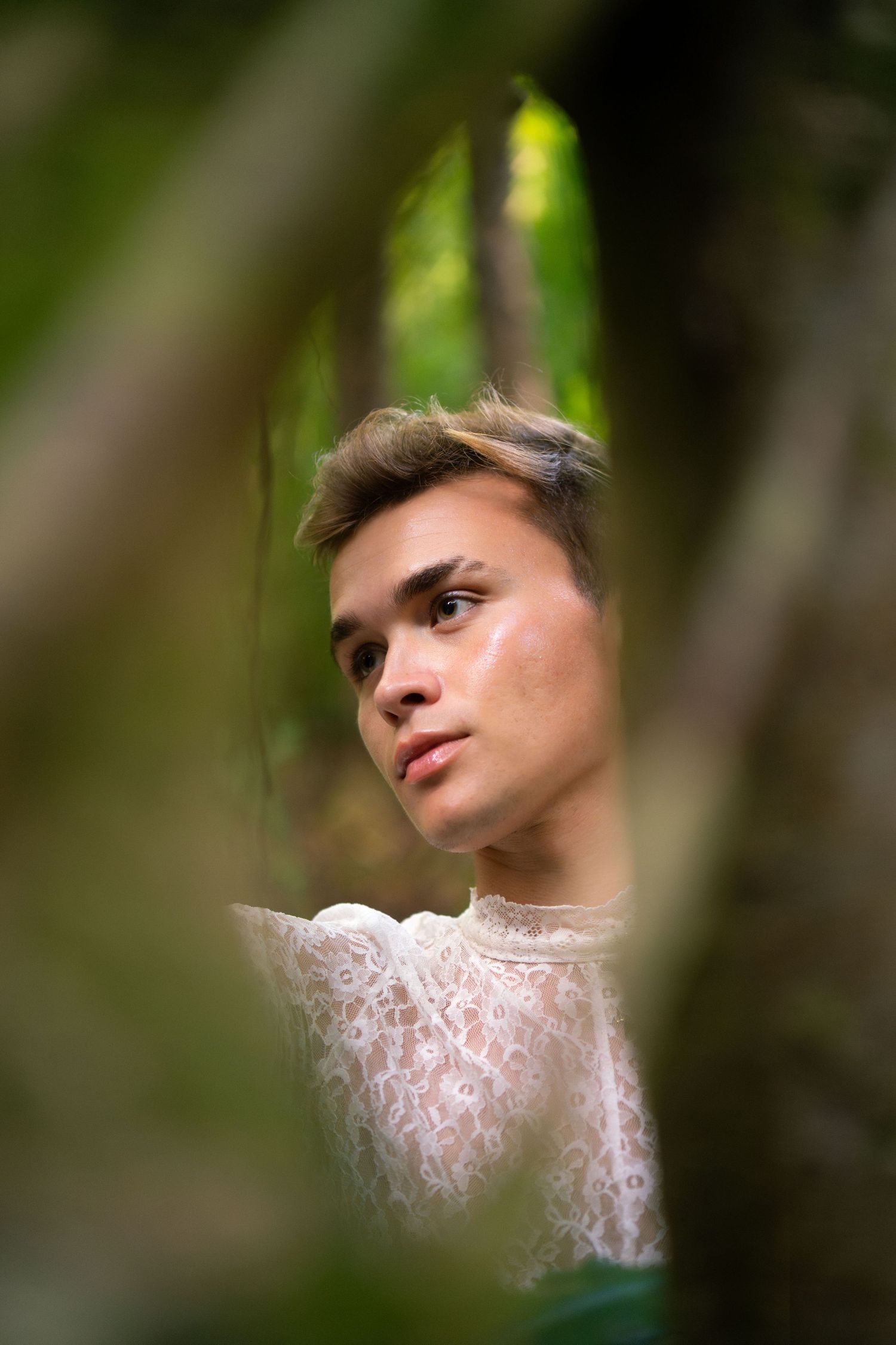 Portrait through foliage showing soft focus and dreamy lighting effects.