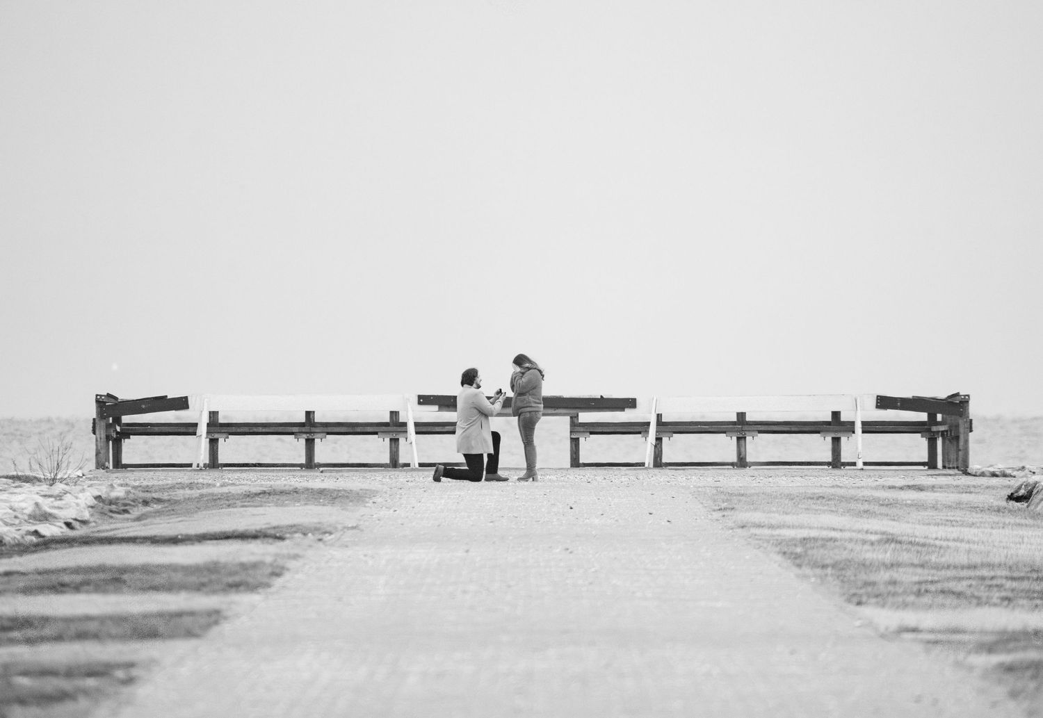 A black and white panoramic photograph shows a wooden fence stretching across a vast empty landscape.