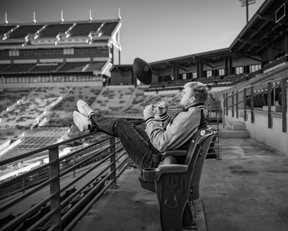 A black and white panoramic sequence of empty stadium seats and bleachers at a sports venue.