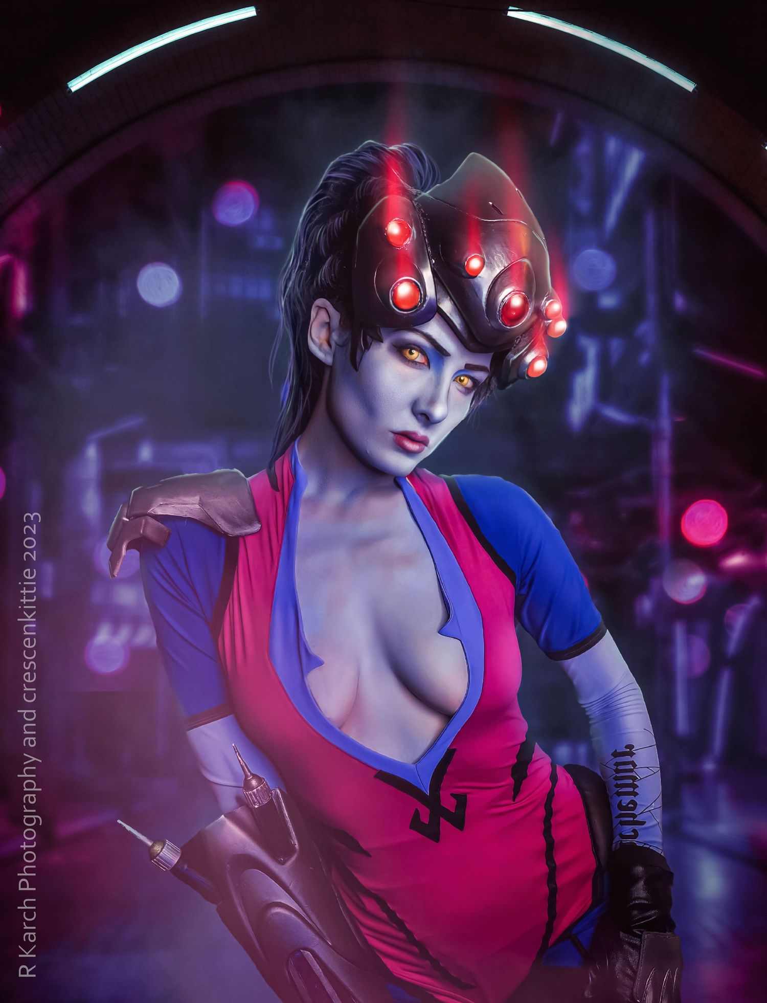 Cyberpunk cosplay with red LED headpiece and matching outfit in neon-lit setting with bokeh effects.