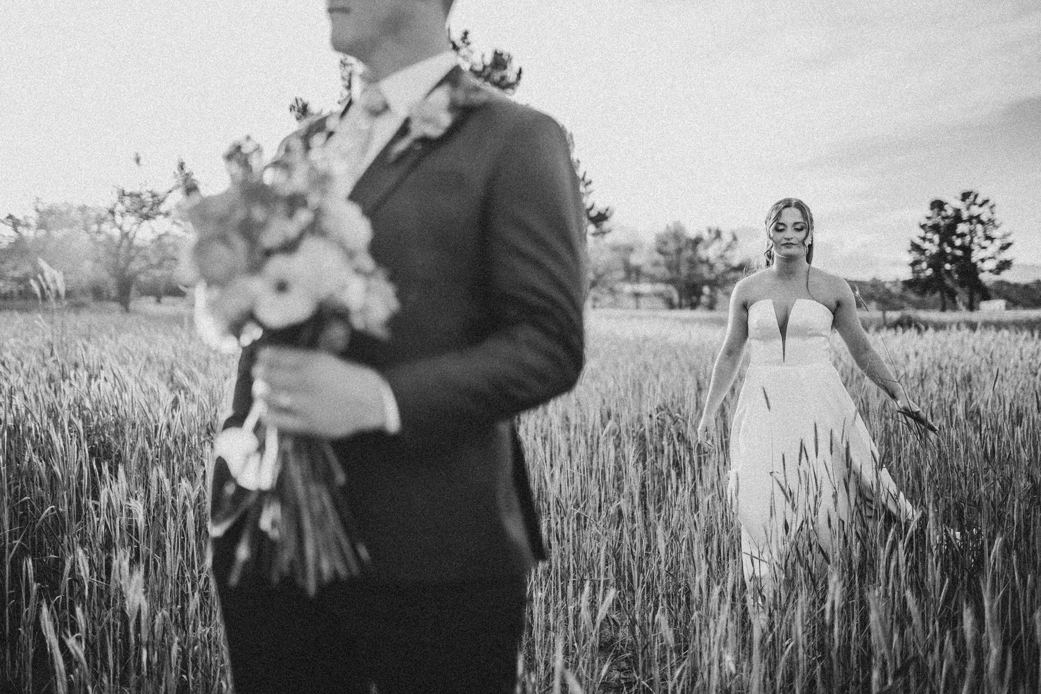 Wedding couple embraces in a golden wheat field during sunset photo session.