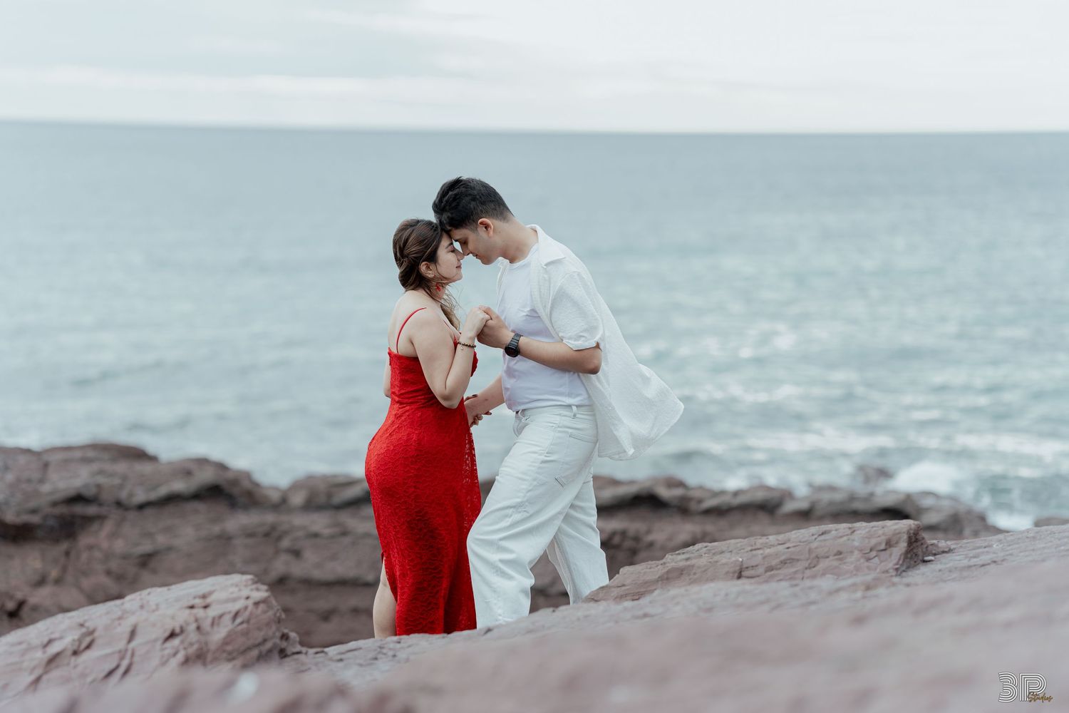 Black and white photo of romantic beach scene with flowing white dress.