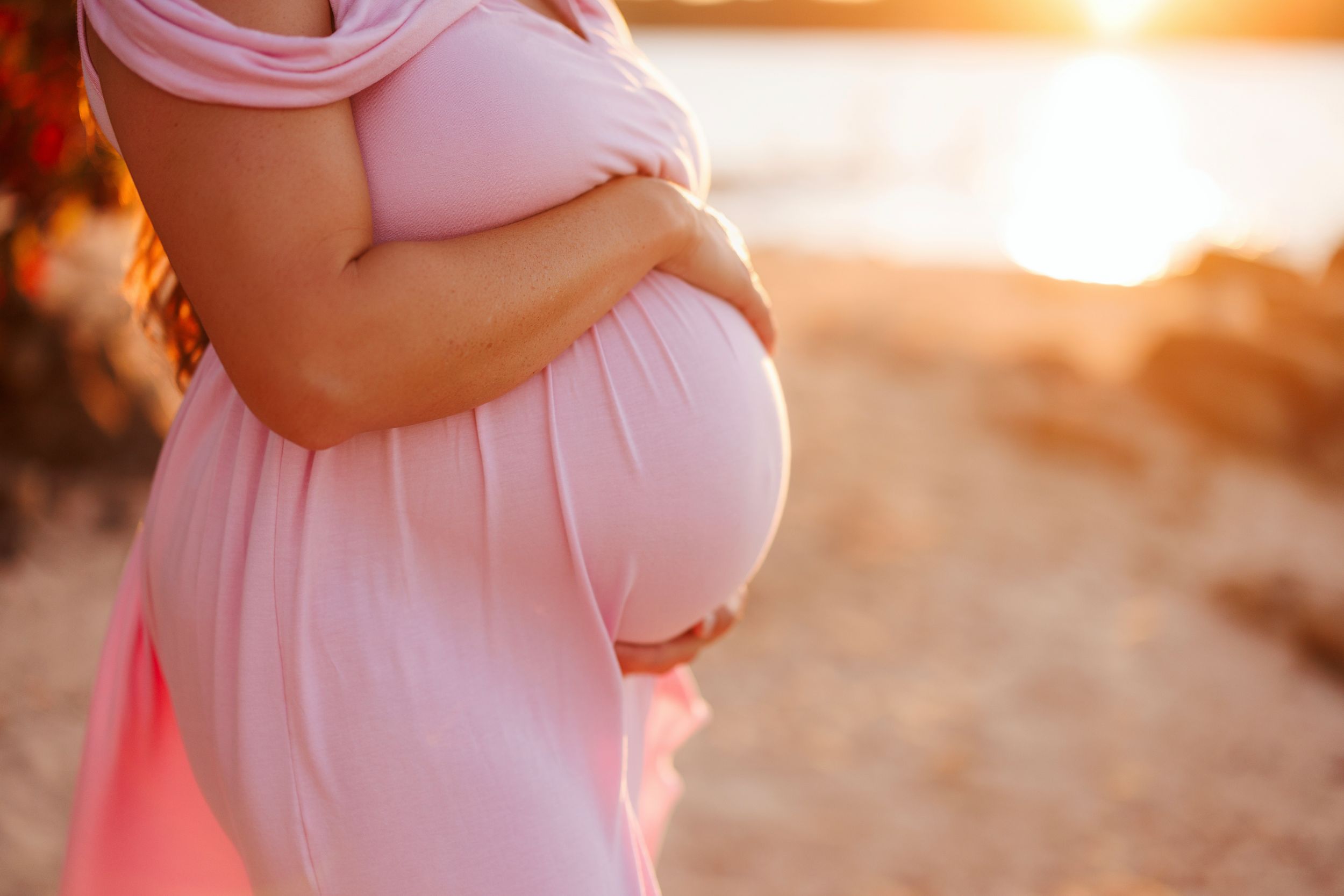 A series of maternity photos showing a pregnant woman's belly in soft pink clothing against a warm sunset backdrop.