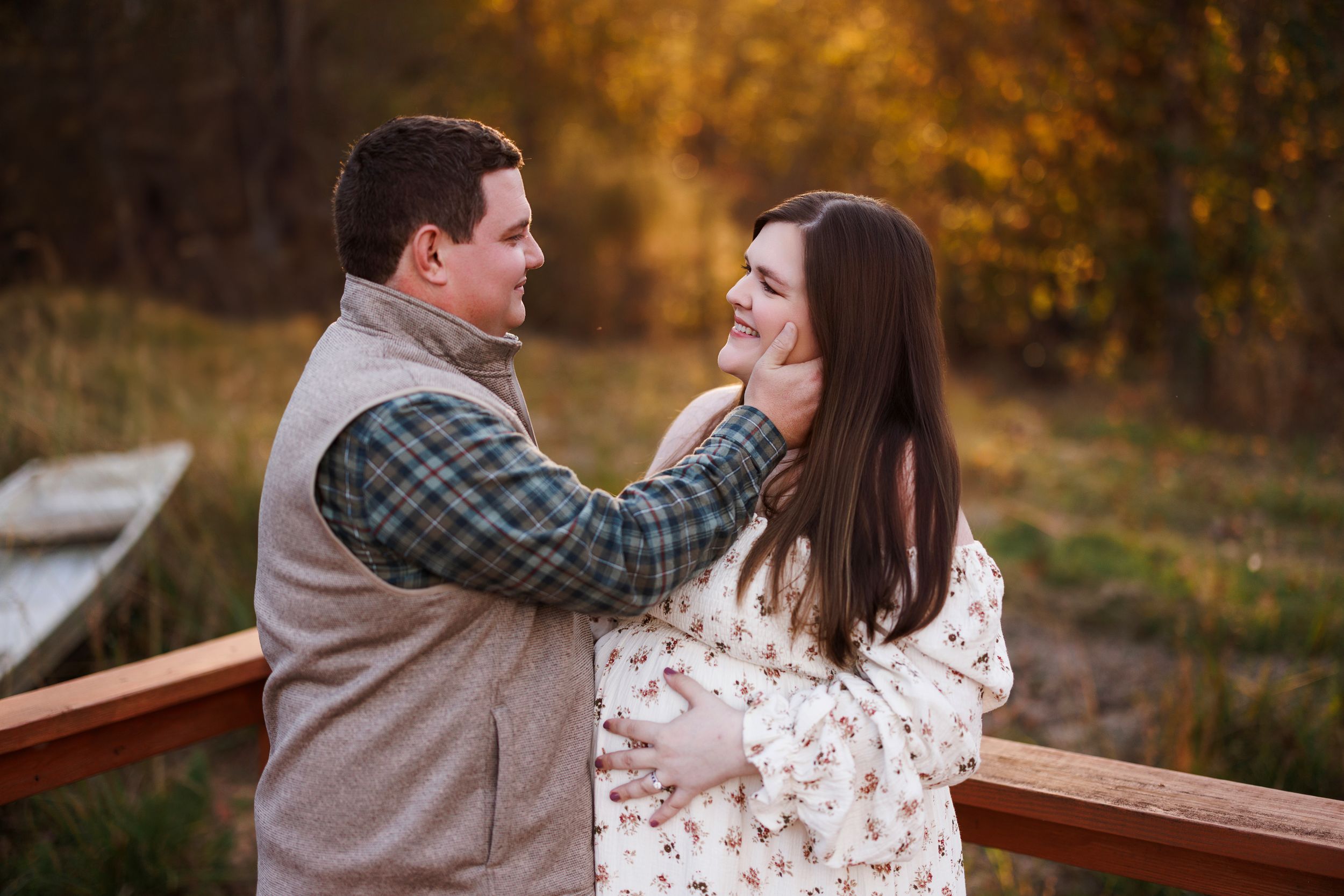 A couple shares a romantic moment outdoors during autumn with golden foliage in the background.
