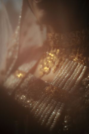Close-up detail of pearl and gold embellishments on traditional wedding dress.