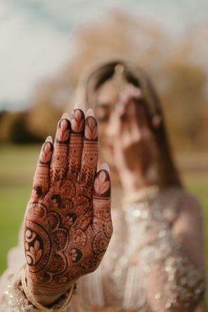 Intricate henna design displayed on a palm with delicate swirls and patterns against an autumn outdoor backdrop.