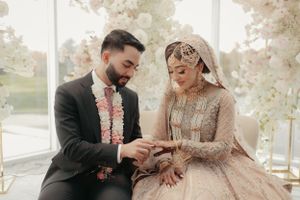 Couple sharing intimate wedding moment in light-filled room with decorative floral arrangements.