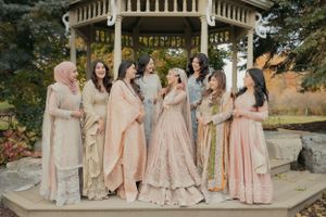 Wedding party in coordinated pastel and neutral outfits posing at gazebo.