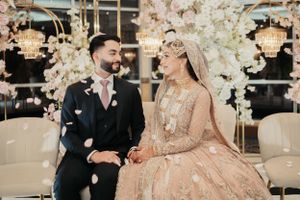 Wedding couple sharing joyful moment surrounded by cherry blossom decorations and chandeliers.