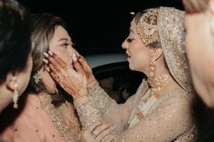 Emotional wedding moment captured between guests in sparkling formal attire.