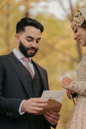 Couple sharing a private moment reading vows during autumn outdoor ceremony.