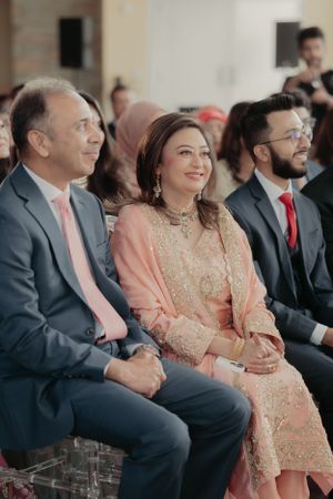 Wedding guests in formal attire watching ceremony from their seats.