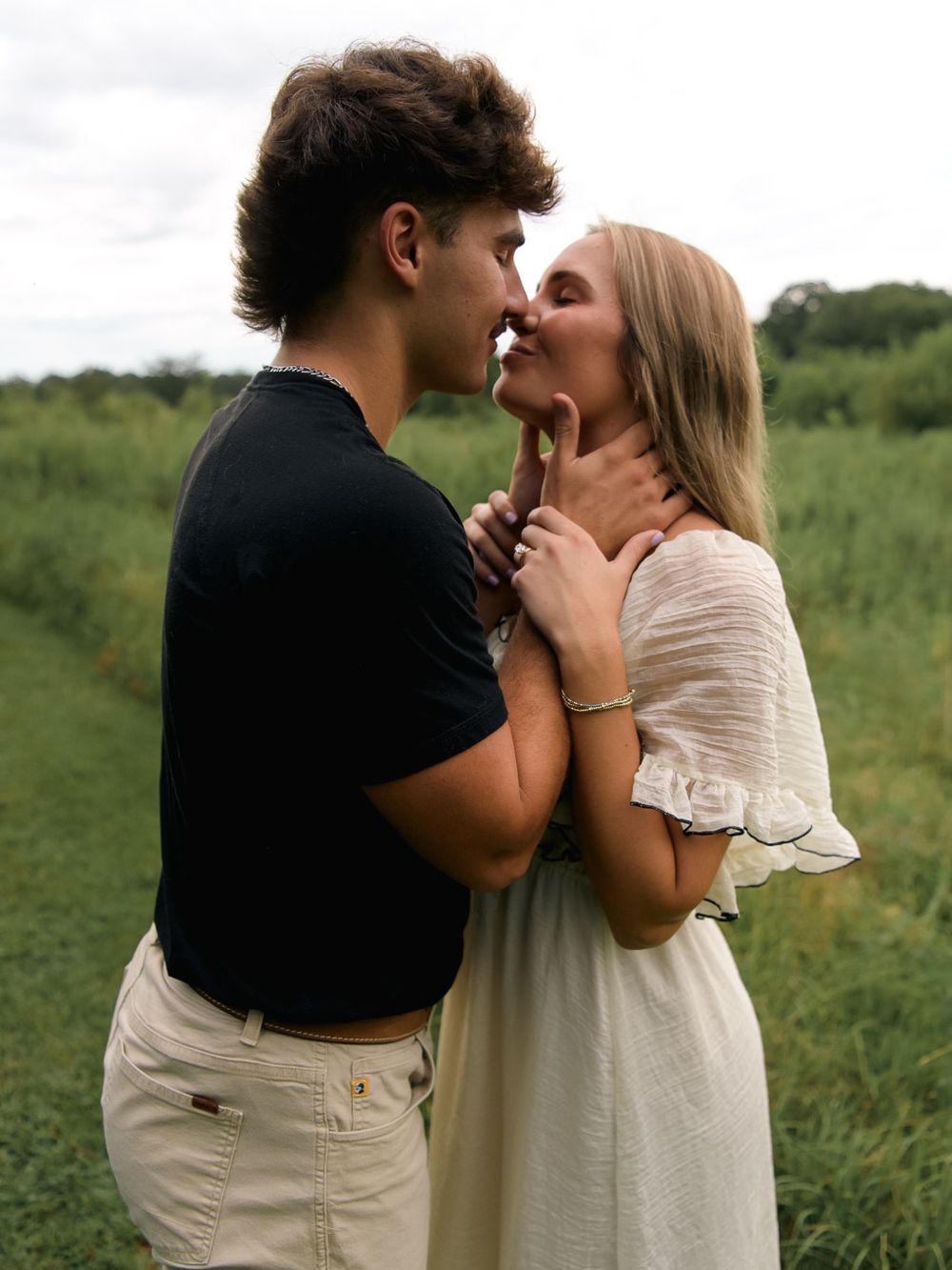 Romantic couple sharing tender moments in a green summer field.