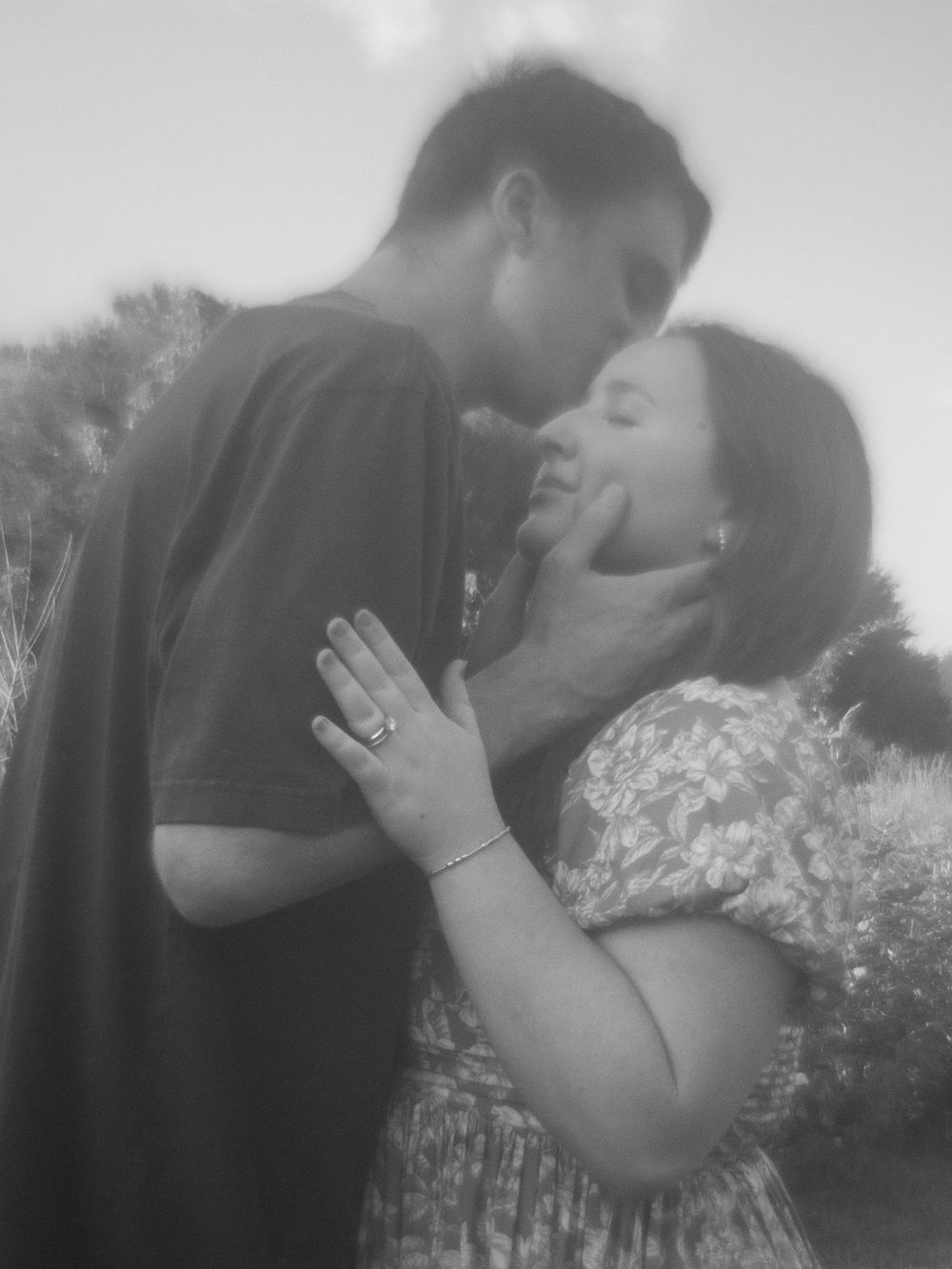 Romantic black and white photo of a couple sharing an intimate moment outdoors.